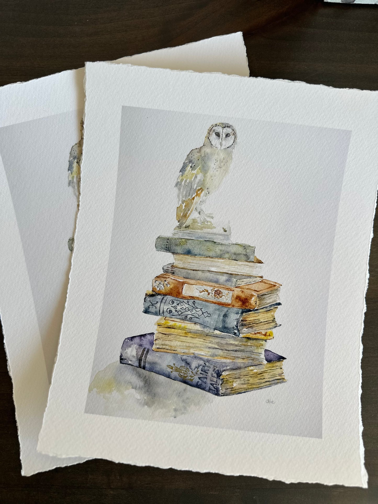 A barn owl rests atop a tower of worn Victorian books, painted in soft watercolor and original painting by Chloe Duncan and giclee print with deckled edges