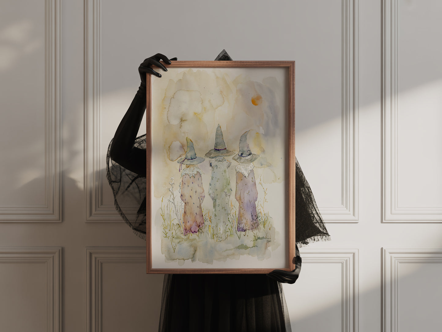 Watercolor Painting of three cloaked witches walking beneath a twilight sky. The figures are silhouetted in soft hues, evoking folklore, mystery, and ancient magic. A moon glows faintly above the horizon.