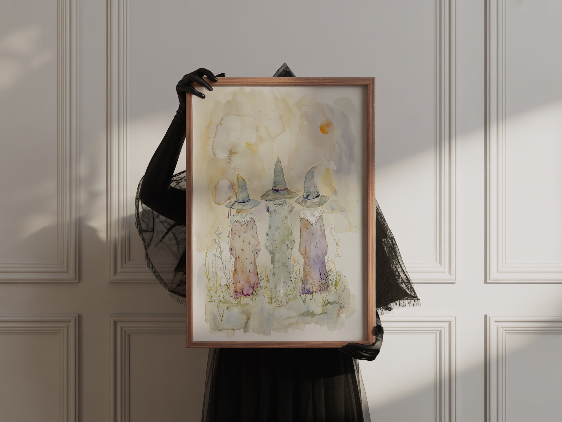 Watercolor Painting of three cloaked witches walking beneath a twilight sky. The figures are silhouetted in soft hues, evoking folklore, mystery, and ancient magic. A moon glows faintly above the horizon.